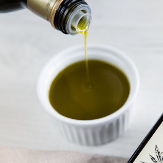 Jemand gießt Bio-Olivenöl in eine Schüssel.