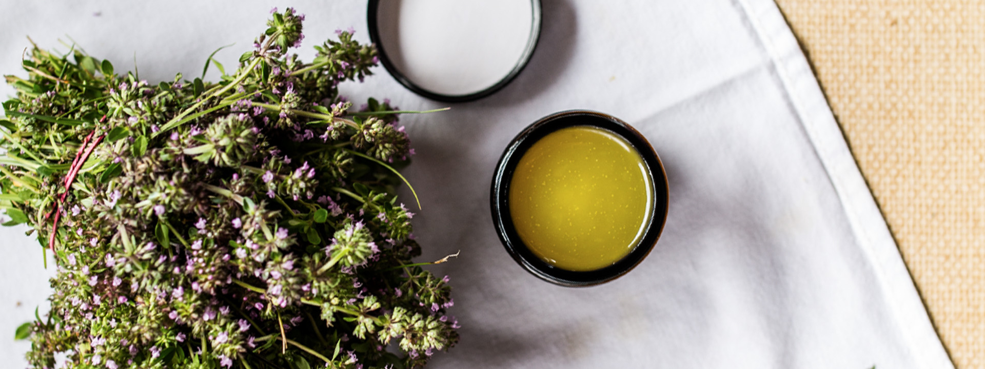 Bio-Thymian und ein Glas Thymian-Balsam auf einem Geschirrtuch.