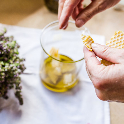 Jemand gibt Bienenwachs in einen Messbecher mit Bio-Öl.