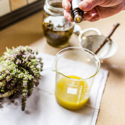 Jemand gibt ätherische Öle zu der Ölschmelze.