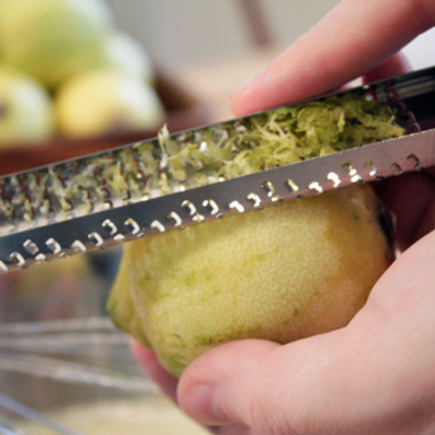 Jemand reibt die Schale einer Bio-Zitrone ab.