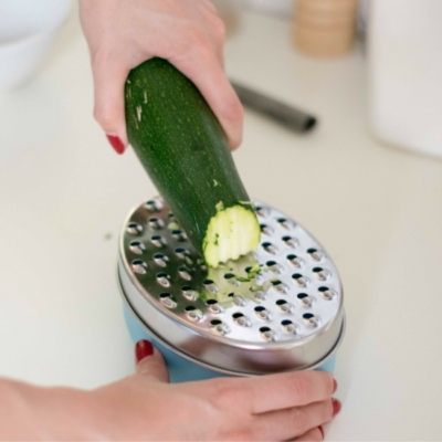 Jemand reibt einen Bio-Zucchini.