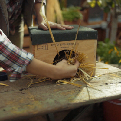 Jemand stopft getrocknetes Streu in eine Igelburg.