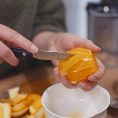 Jemand schneidet eine geschälte Bio-Orange.