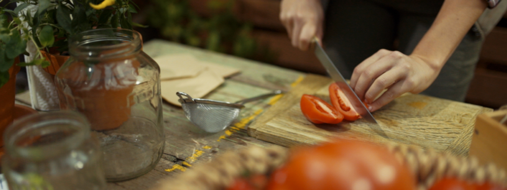 Jemand schneidet Bio-Paradeiser.