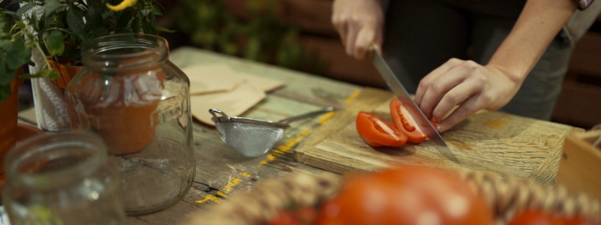 Jemand schneidet Bio-Paradeiser.