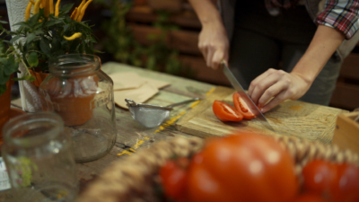 Jemand schneidet Bio-Paradeiser.