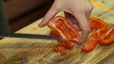 Jemand schneidet Bio-Paradeiser.