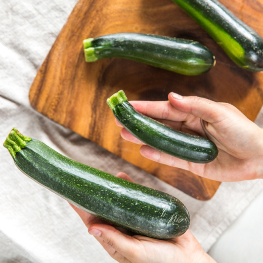 Jemand hält Bio-Zucchinis.