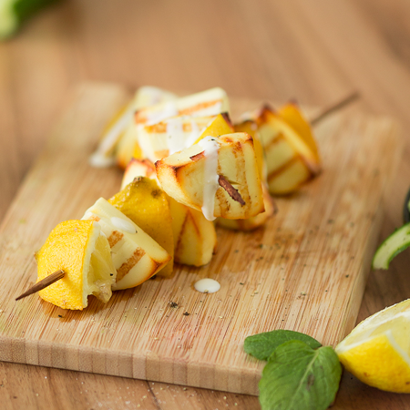 Bio-Grillkäse- und Zitronenspieße auf einem Holzbrett.