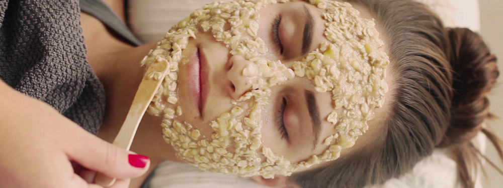 Jemand trägt einer Frau eine Bio-Hafermaske im Gesicht auf.