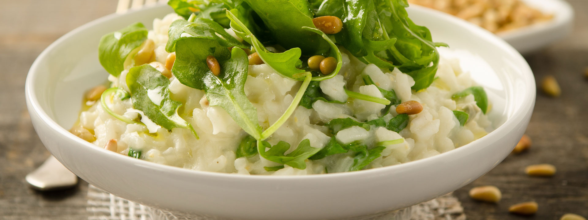 Eine Schale mit Bio-Rucolarisotto mit Pinienkernen und Bergkäse.