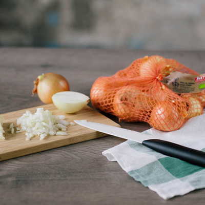 Auf einem Brett liegen geschnittene und ganze Bio-Zwiebeln.