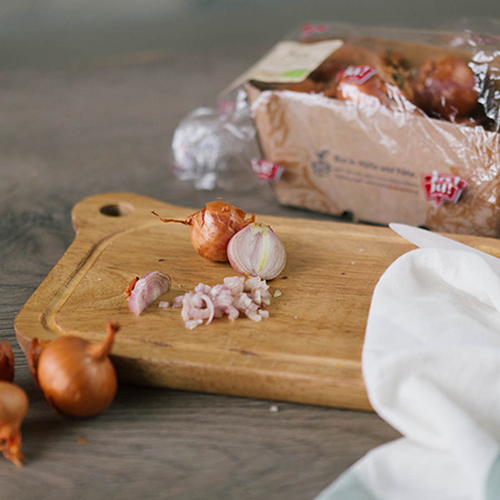 Auf einem Brett liegen geschnittene Bio-Schalotten.