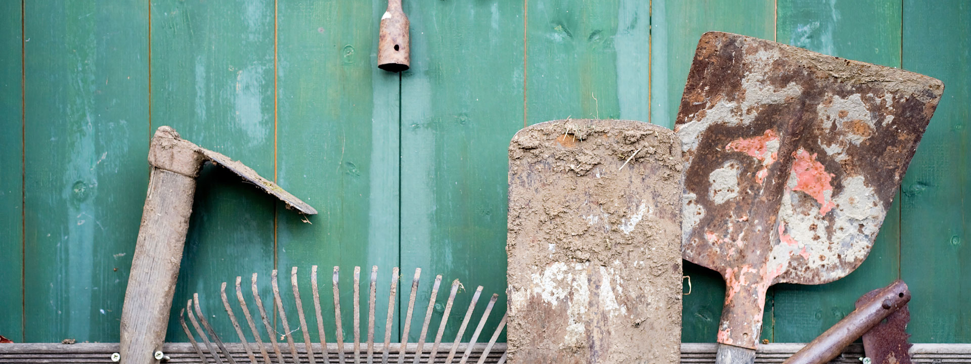 Verschlammte Gartenutensilien wie Schaufeln und Rechen.