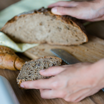 Jemand schneidet sich eine Scheibe Bio-Brot herunter.