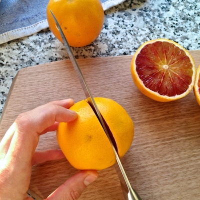 Jemand halbiert Bio-Blutorangen.