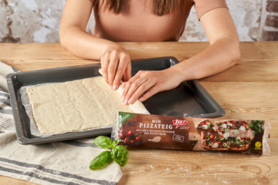 Pizzateig auf Backblech ausrollen