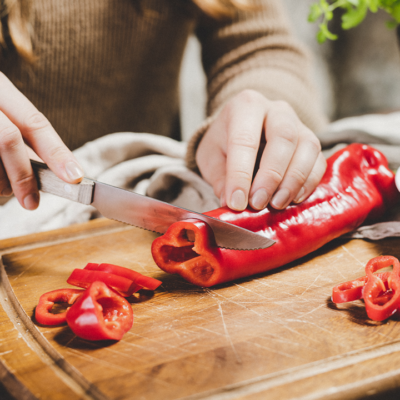 Jemand schneidet eine rote Bio-Paprika.