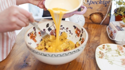 Jemand gießt aufgeschlagene Bio-Eier in eine Schüssel.