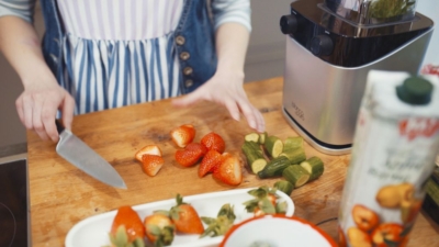 Jemand schneidet Bio-Erdbeeren auf einem Holzbrett.