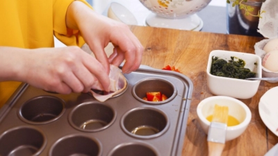 Jemand gibt Bio-Gemüse in Muffinformen.