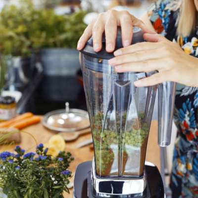 Jemand mixt mit einem Standmixer Bio-Erbsen mit Hummus.