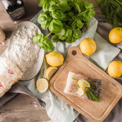 Ein Stück Karpfen mit Zitronenscheibe und Bio-Dill auf einem Brett.