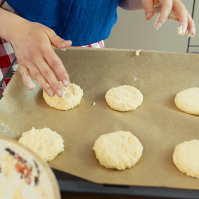 Jemand formt mit dem Teig Laibchen auf einem Backpapier.