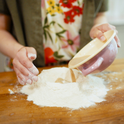 Jemand gießt Milch auf Bio-Mehl.