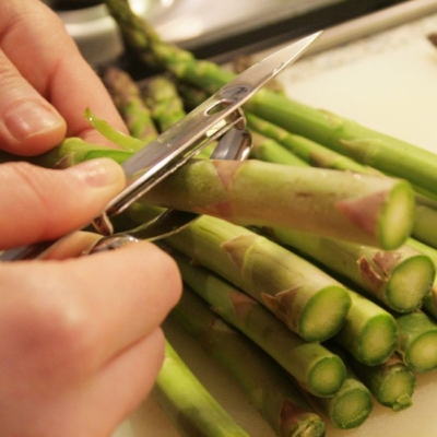 Jemand schält grünen Bio-Spargel.