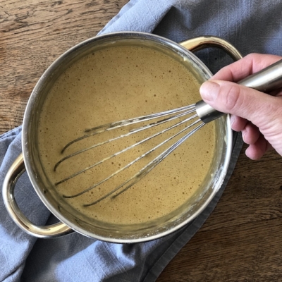 Jemand rührt mit einem Schneebesen den Teig in einem Topf an.