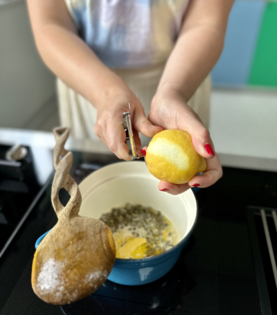 Jemand schält Bio-Zitronen und gibt sie in einen Topf.