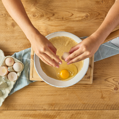 Jemand schlägt ein Bio-Ei über eine Galette auf.
