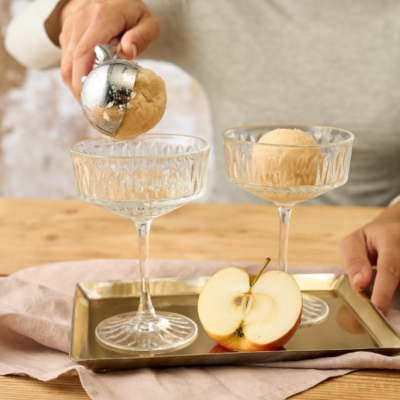 Jemand gibt Sorbetkugeln in Gläser.