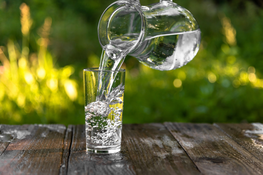 Jemand schüttet Wasser in ein Glas.