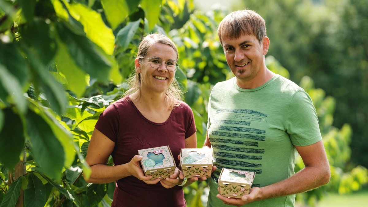 Familie Köck hält verpackte Bio-Papau von Ja! Natürlich