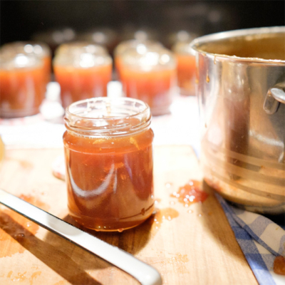 Marmeladengläser mit Bitterorangenmarmelade und einem Kochtopf.