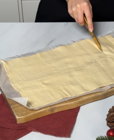 Jemand schneidet Bio-Blätterteig auf einem Schneidebrett.