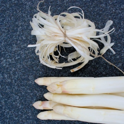 Bio-Spargel und Spargelschalen auf einem Schneidebrett.