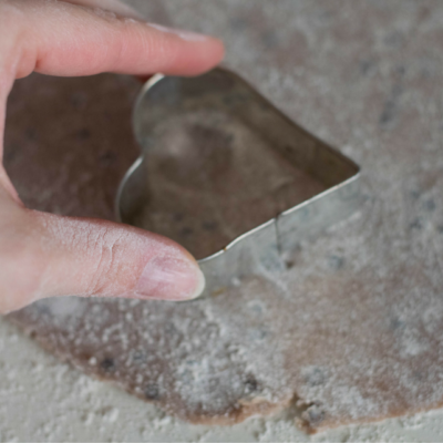 Jemand sticht Kekse mit einem Herzausstecher aus einem Bio-Teig.