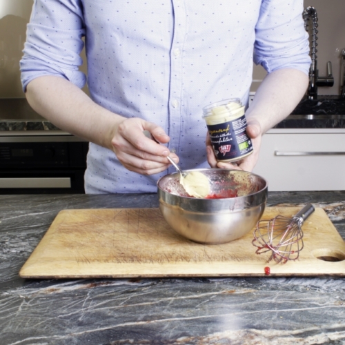 Ja! Natürlich Bio-Estragon-Senf und Ribiselkonfitüre werden in einer Schüssel zusammengerührt.