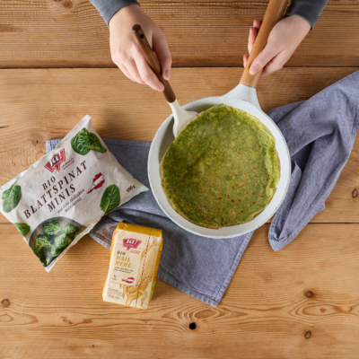 Jemand macht Spinat-Tortillas mit Ja! Natürlich Bio-Maismehl und Blattspinat.