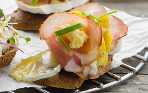 Abkühlgitter, auf dem Kornspitzbaguettes mit Bio-Camembert, Kaiserspeck und Eierspeis liegen.