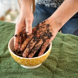 Jemand reibt ein Kaffeepeeling auf seine Hände.