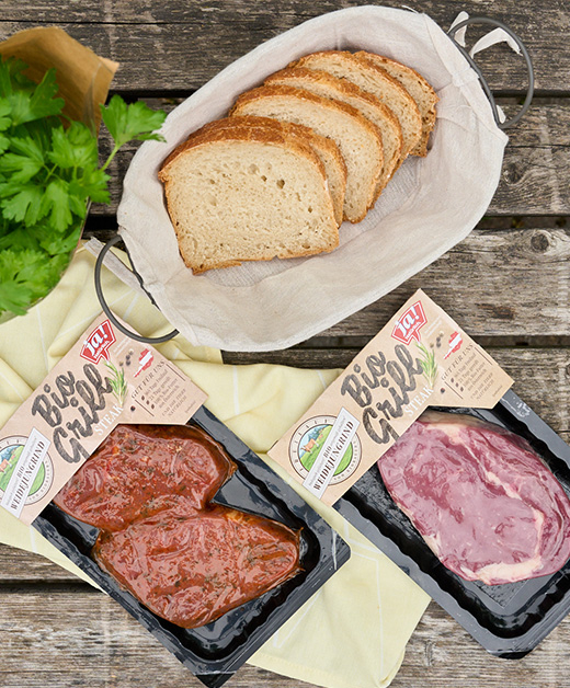 Tisch mit Ja! Natürlich Bio-Grillsteaks und Brot.