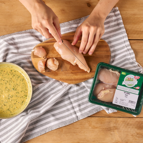 Bio-Hähnchenbrustfilet wird auf einem Holzbrett für Hühnerspieße geschnitten.