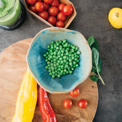 Eine Schüssel mit Bio-Erbsen und weiterem Gemüse rundherum.