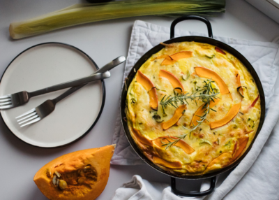 Frischkäse-Frittata mit Bio-Kürbis, Lauch und Reisresten in einer Gusseisen-Bratpfanne.