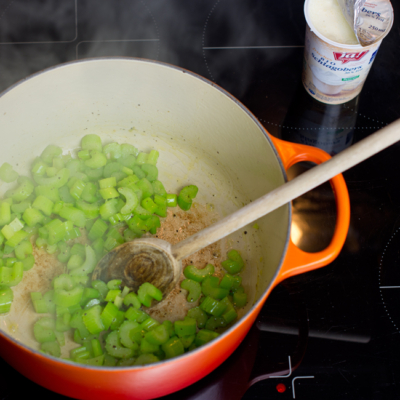Ein Topf, in dem Bio-Stangensellerie angeröstet wird. Dahinter steht ein Becher Ja! Natürlich Bio-Schlagobers.